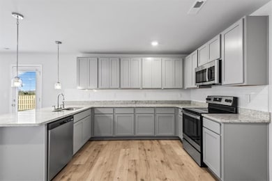 Kitchen with stainless steel appliances, a sink, a peninsula, gray cabinetry, and recessed lighting