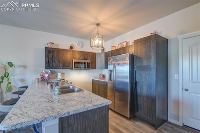 Kitchen featuring appliances with stainless steel finishes, a peninsula, light countertops, light wood-type flooring, and a chandelier