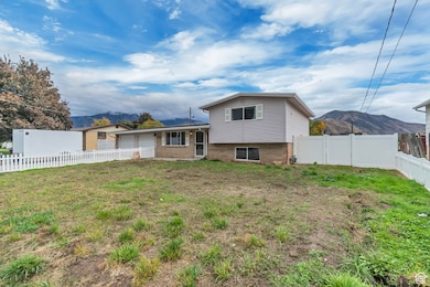 Rear view of house with brick siding, a fenced backyard, a mountain view, a garage, and driveway