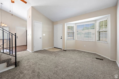 Unfurnished room featuring stairs, vaulted ceiling, carpet floors, and a ceiling fan