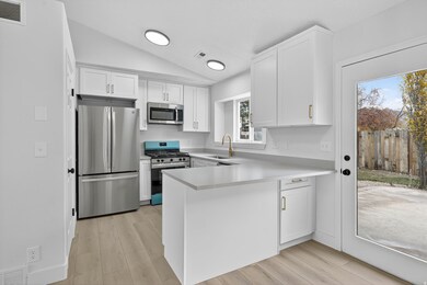 Kitchen with white cabinetry, light countertops, lofted ceiling, stainless steel appliances, and light wood-style floors