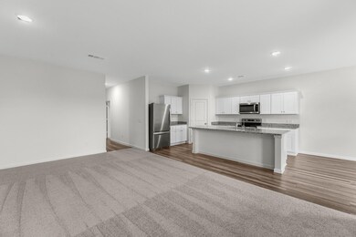 Kitchen featuring recessed lighting, open floor plan, white cabinets, appliances with stainless steel finishes, and a kitchen island with sink