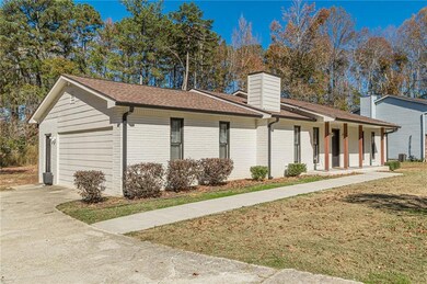 View of property exterior featuring covered porch, roof with shingles, driveway, a yard, and a chimney