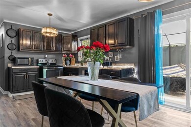 Kitchen featuring black microwave, electric range, light wood-type flooring, dark brown cabinetry, and light countertops