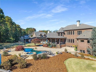 Rear view of property featuring a chimney, a patio area, a pool with connected hot tub, and brick siding