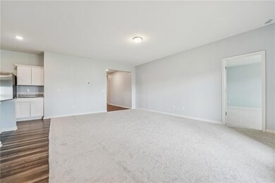Unfurnished living room featuring baseboards and dark carpet