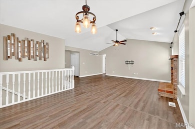 Unfurnished living room with vaulted ceiling, wood finished floors, a chandelier, and a ceiling fan