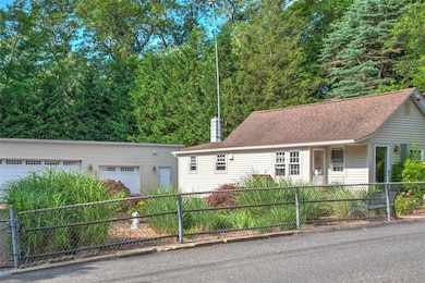 View of front facade featuring a fenced front yard, a detached garage, a chimney, and roof with shingles