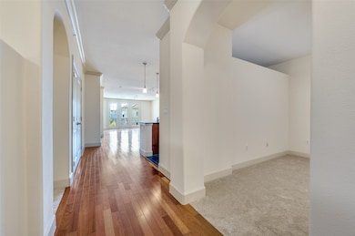 Corridor featuring arched walkways, light wood-style flooring, french doors, and light colored carpet