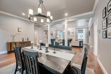 Dining space featuring crown molding, ornate columns, a fireplace, hardwood / wood-style floors, and a notable chandelier