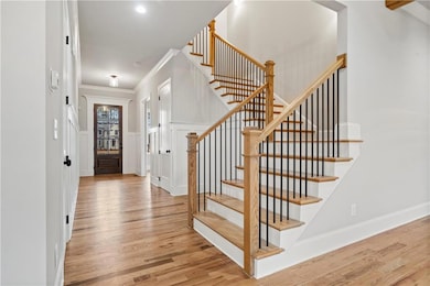 Foyer entrance featuring light wood-type flooring, ornamental molding, a decorative wall, and stairs