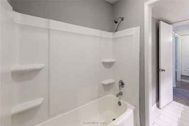 Bathroom featuring washtub / shower combination and baseboards