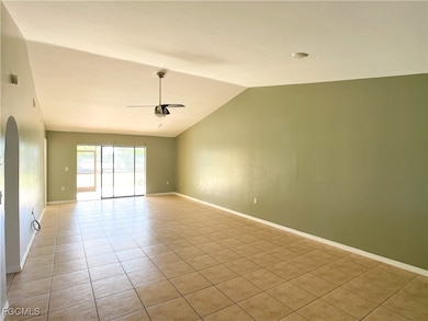 Spare room featuring light tile patterned floors, lofted ceiling, arched walkways, and a ceiling fan