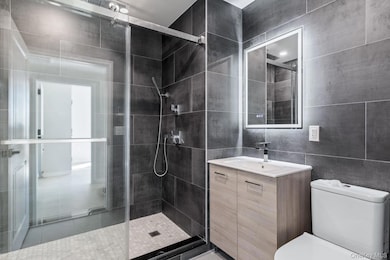 Bathroom with a shower stall, vanity, and tile walls