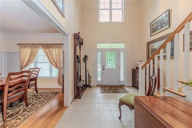 Foyer featuring healthy amount of natural light, a towering ceiling, light tile patterned flooring, and stairs