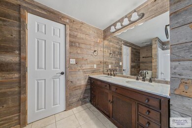 Bathroom with vanity, wood walls, and tile patterned flooring