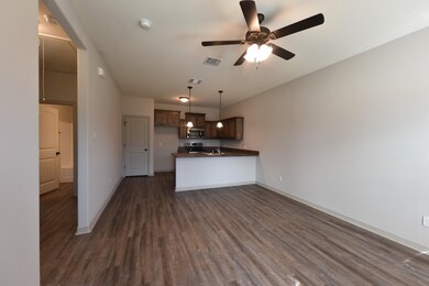 Kitchen with dark countertops, decorative light fixtures, dark wood finished floors, a peninsula, and open floor plan