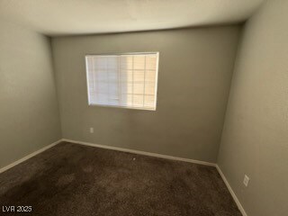 Empty room featuring dark carpet and baseboards