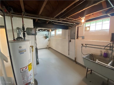 Below grade area featuring water heater and electric panel