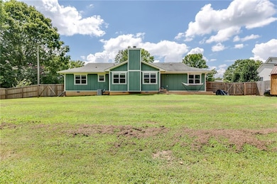 Rear view of house featuring crawl space, a fenced backyard, and roof with shingles