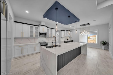 Kitchen featuring white cabinets, a sink, pendant
