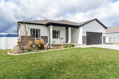 View of front facade with a porch, stone siding, concrete driveway, an attached garage, and roof with shingles