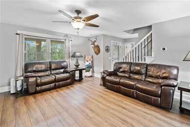 Living room with a ceiling fan, wood finished floors, stairway, and baseboards