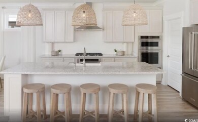 Kitchen with appliances with stainless steel finishes, a kitchen bar, light wood-type flooring, and light stone counters