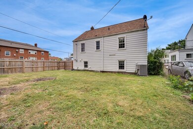 Rear view of property with central air condition unit and a lawn