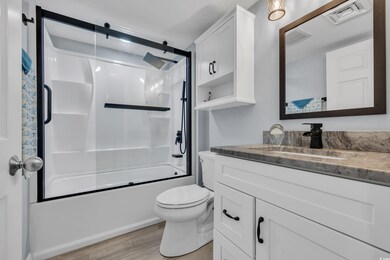 Full bathroom featuring vanity, wood finished floors, toilet, and bath / shower combo with glass door