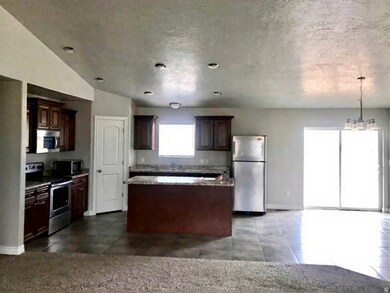 Kitchen with stainless steel appliances, a kitchen island, hanging light fixtures, dark brown cabinets, and a chandelier