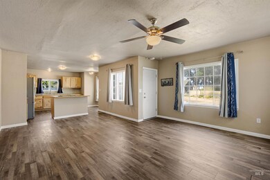 Unfurnished living room featuring a textured ceiling, plenty of natural light, dark wood-style flooring, and a ceiling fan