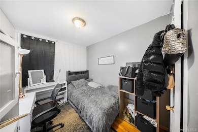 Bedroom with wood finished floors and an office area