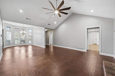 Unfurnished living room with high vaulted ceiling, dark wood-style floors, a ceiling fan, a chandelier, and recessed lighting