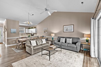 Living area featuring a chandelier, wood finished floors, ceiling fan, and high vaulted ceiling