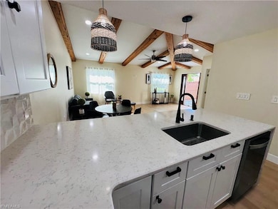 Kitchen featuring open floor plan, light wood-style floors, white cabinets, light stone countertops, and hanging light fixtures
