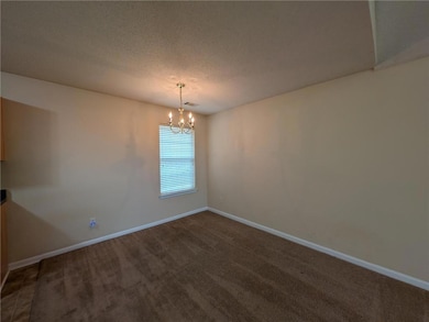 Carpeted spare room with baseboards, a textured ce