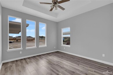 Unfurnished room with a tray ceiling, ceiling fan, and wood finished floors