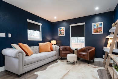 Living room featuring a textured wall, wood finished floors, and recessed lighting