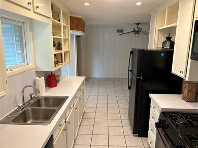 Kitchen with white cabinetry, black appliances, tile floors