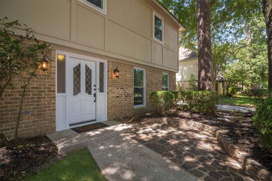 Just outside the front door is a stone paved patio area partially secluded with landscaping and tall mature trees.