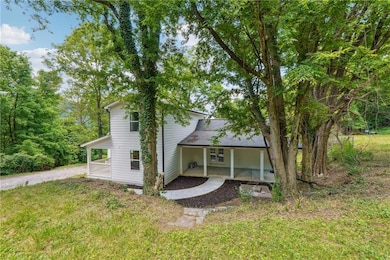 Rear view of house featuring driveway, a yard, and covered porch