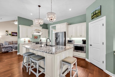 Kitchen with stainless steel appliances, a sink, a breakfast bar area, white cabinetry, and light stone countertops