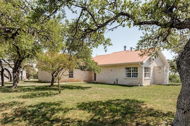 Back of property with stone siding, metal roof, a