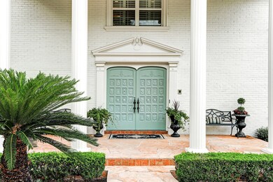 A closer look at the intricate double wood doors and the detailed woodwork on the covered front porch