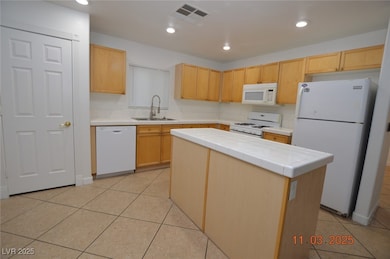 Kitchen with white appliances, tile counters, a kitchen island, recessed lighting, and light tile patterned floors