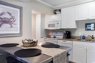 Kitchen featuring crown molding, sink, white appli