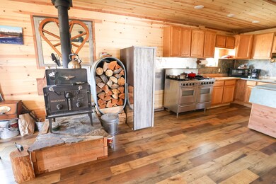 Kitchen featuring a wood stove, range with two ovens, wooden walls, hardwood / wood-style flooring, and wood ceiling
