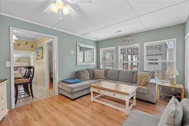 Living room featuring plenty of natural light, light wood-style flooring, a ceiling fan, and crown molding