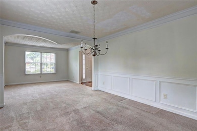 Carpeted spare room featuring a chandelier, orname
